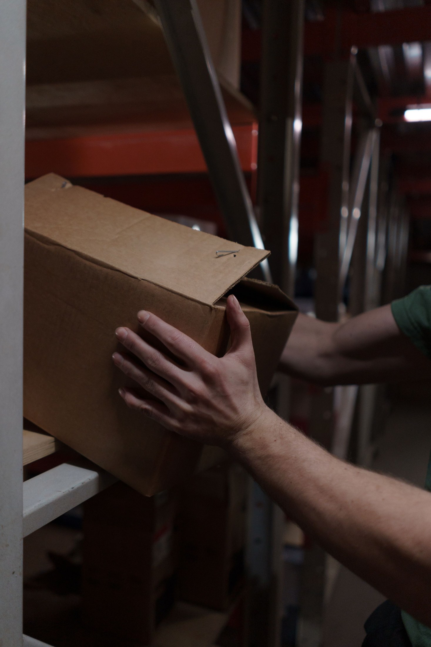 Close view of a worker placing a cardboard carton on a shelf